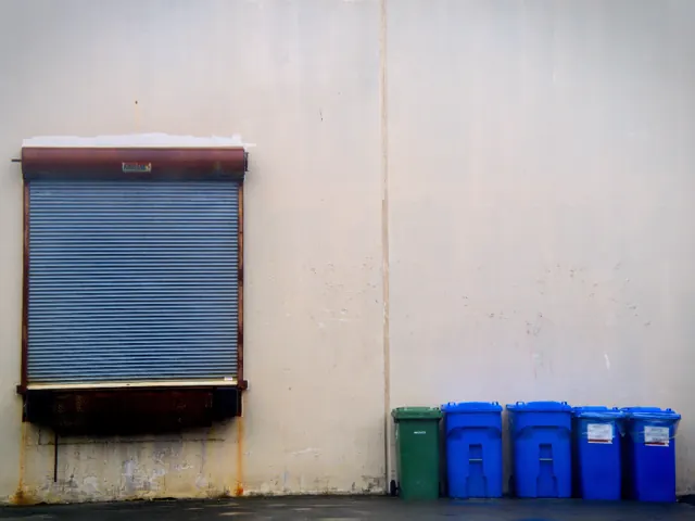 Recycling bins lined up by a wall