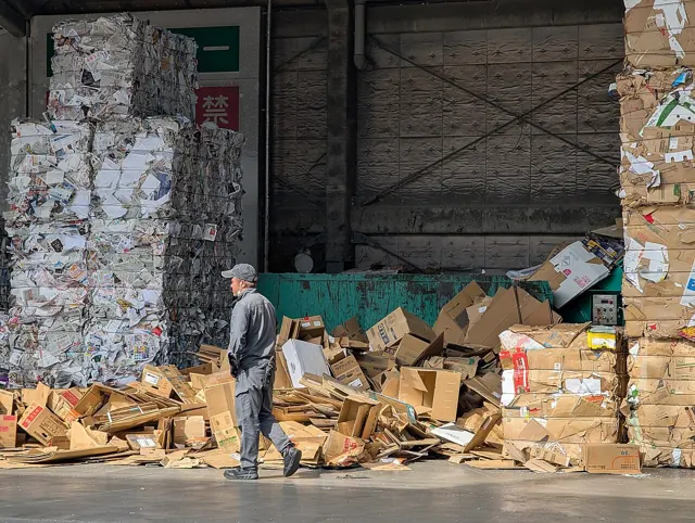 Cardboard and paper being sorted at a recycling yard